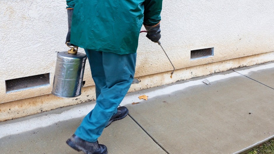 Extreme Termite and Pest Control technician sprays the outside of a commercial property in Pensacola Florida.