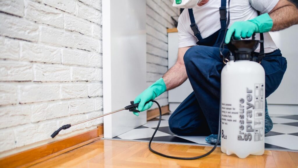Pest control technician applying cockroach control method to a Pensacola home.